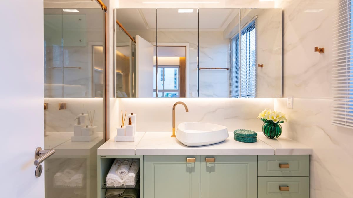 Bathroom with a sage green vanity, a vessel sink and mirrored cabinets