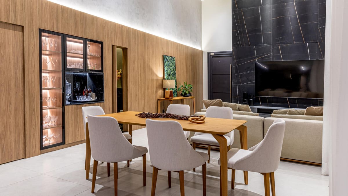 Dining and living room with wood paneling, a lit display cabinet and a stone media wall