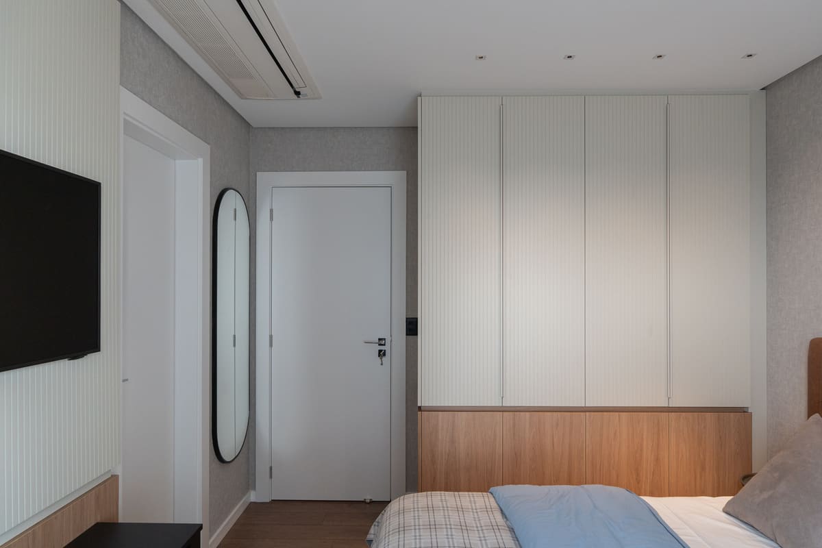 Bedroom with a fluted white wardrobe above a wood base