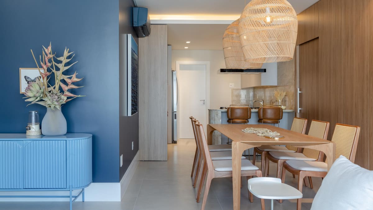 Dining room with a wood table, cane chairs, a woven pendant and a deep blue wall