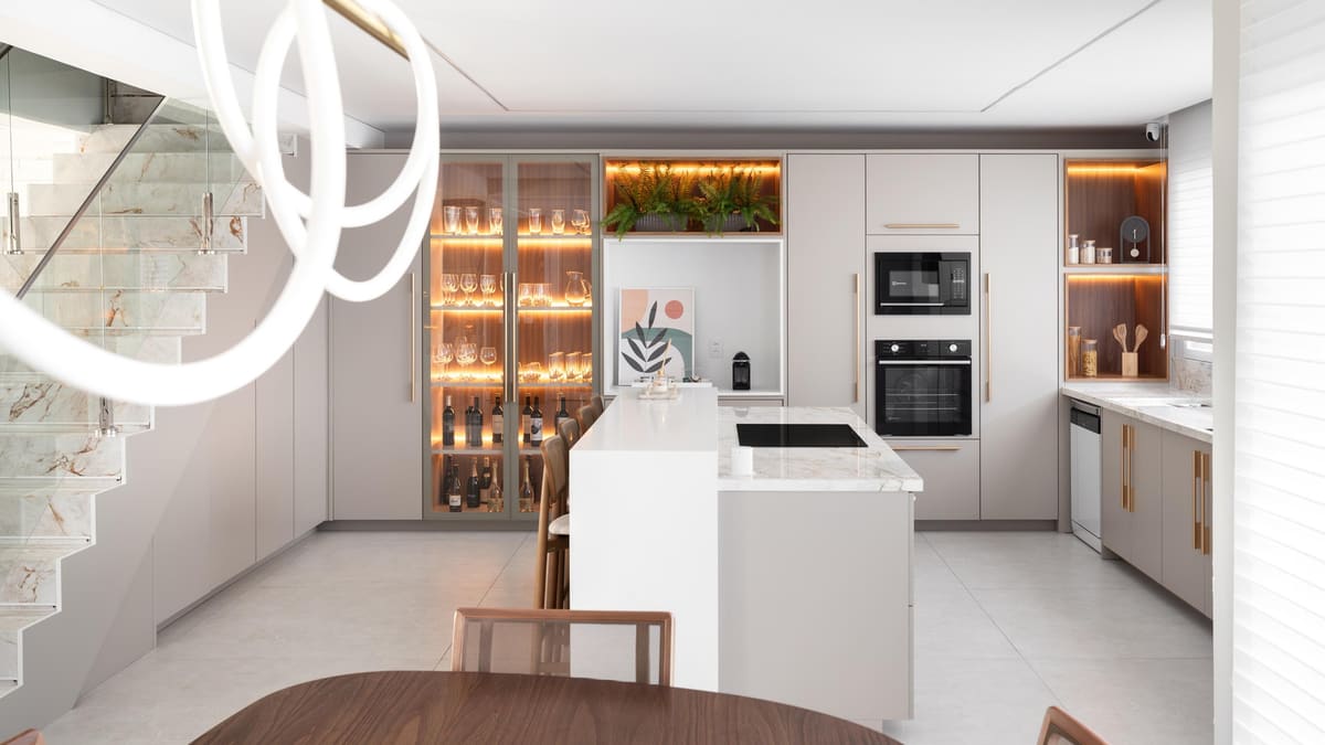 White kitchen with an island, a lit glass-front pantry and a sculptural ring pendant