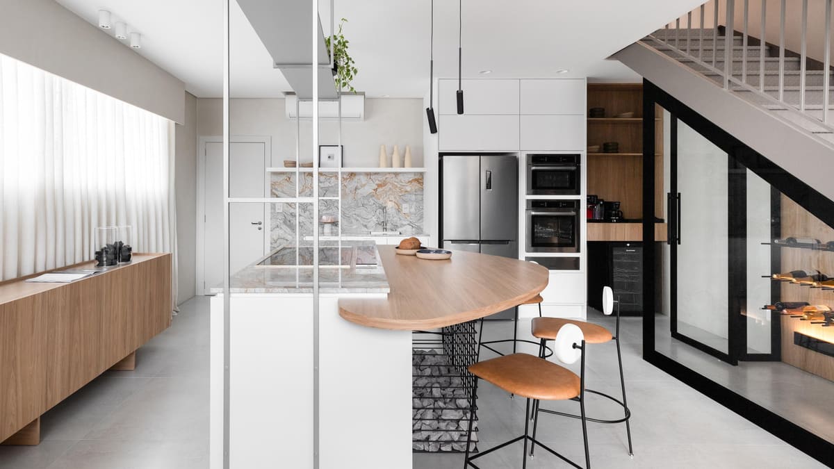 Kitchen with a curved wood breakfast counter, a glass partition and storage under the stairs