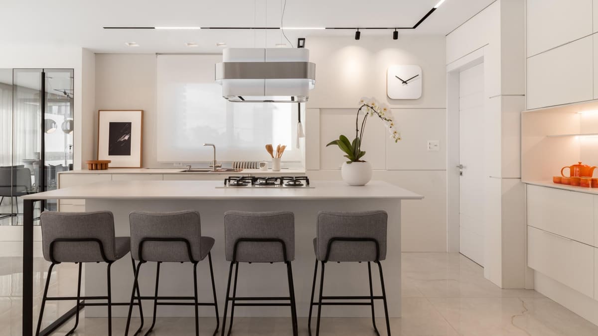 White kitchen with a cooktop island, grey bar stools and a suspended hood