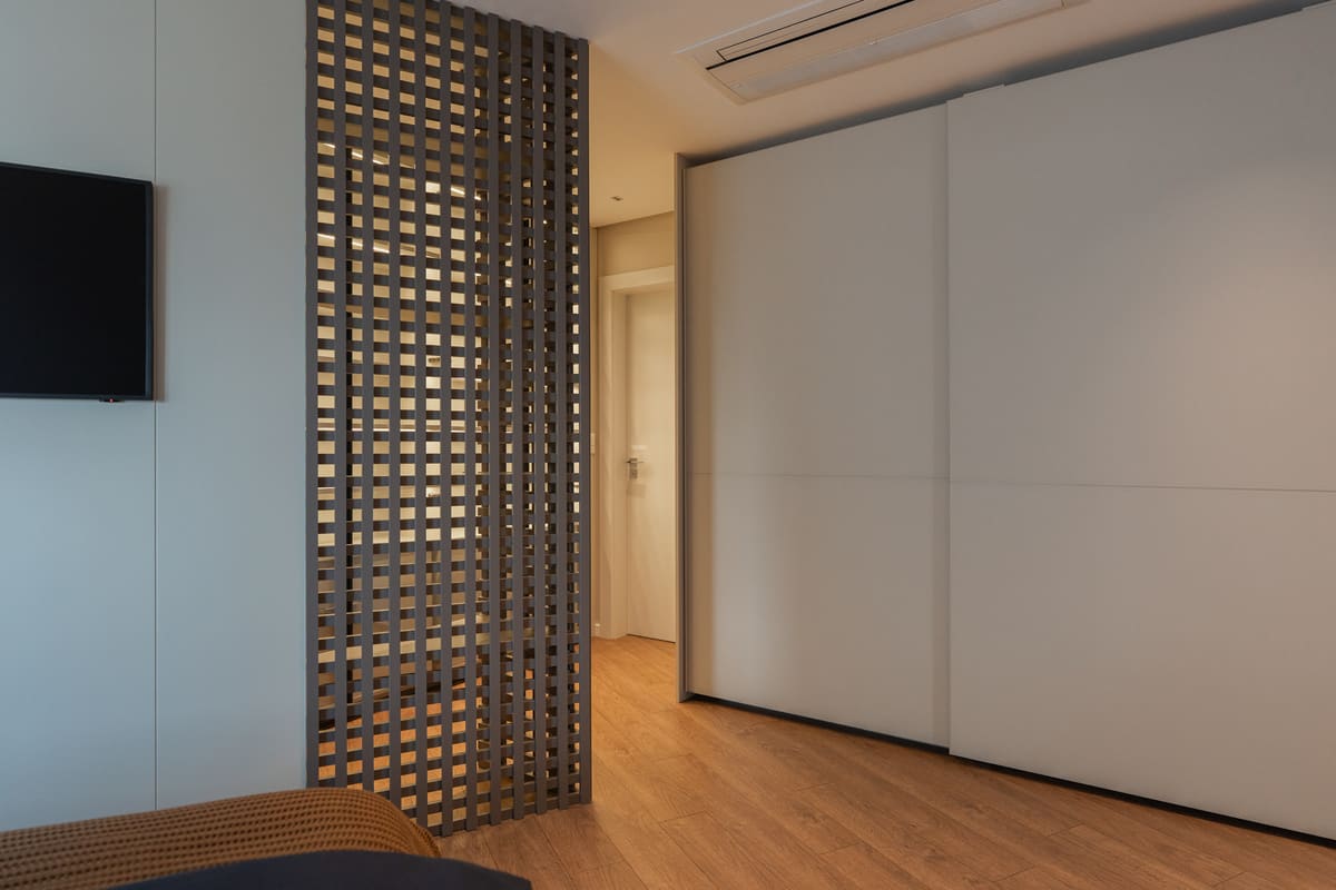 Bedroom divided by a dark wood lattice screen beside a sliding wardrobe